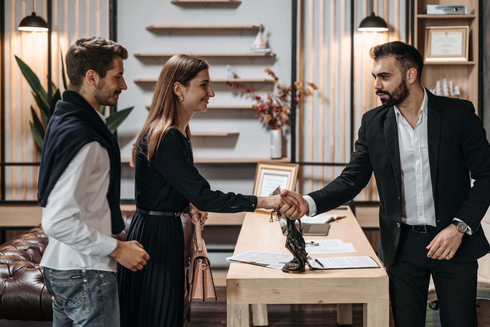A professional meeting in a modern office with a couple shaking hands with a businessman